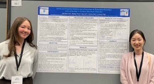Two women standing on either side of a poster presentation