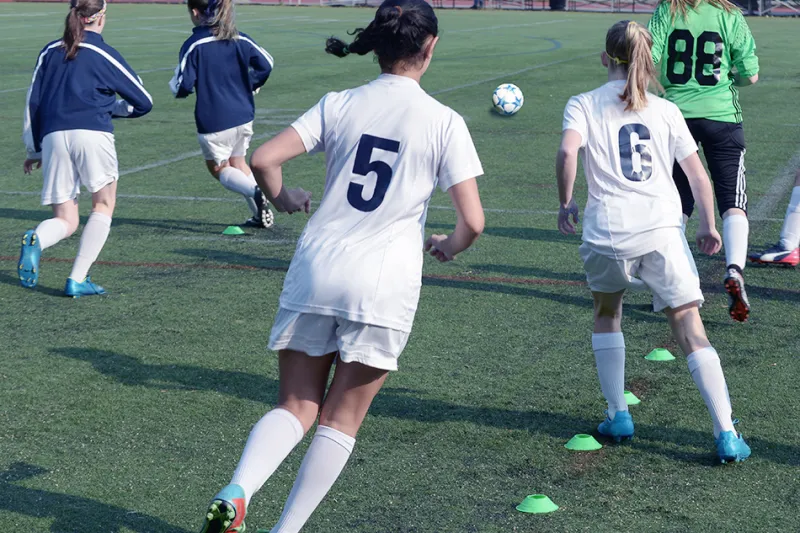 Girls soccer players do agility drills at practice