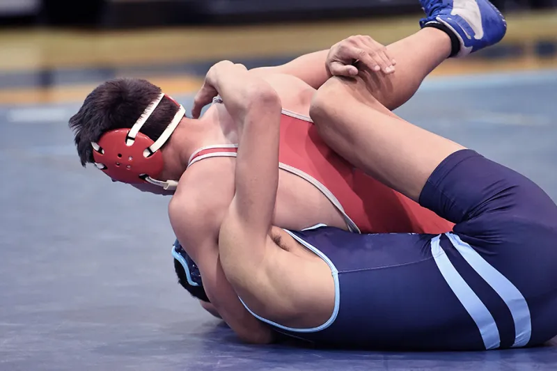 A wrestler pins his opponent to the mat