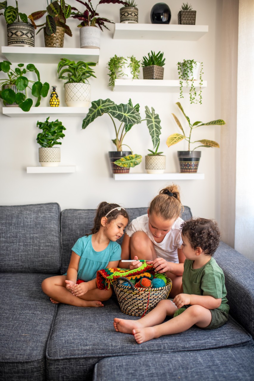 young children on a couch watching one of them knit