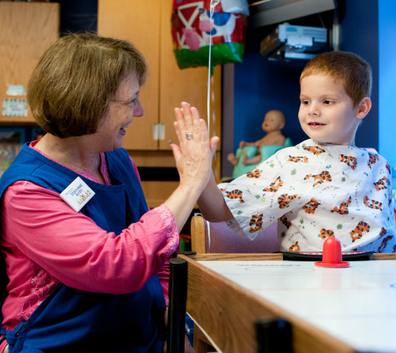 Hospital volunteer high fives patient getting discharged