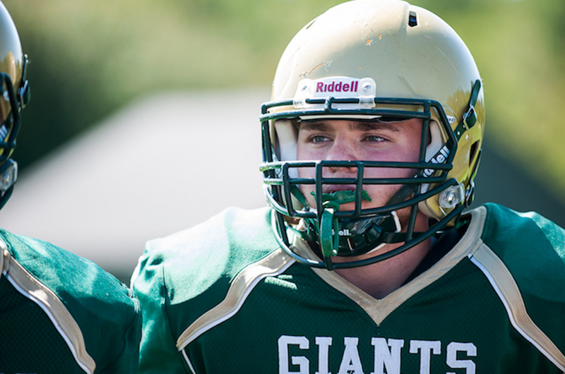 Boy, standing, wearing full high school football uniform