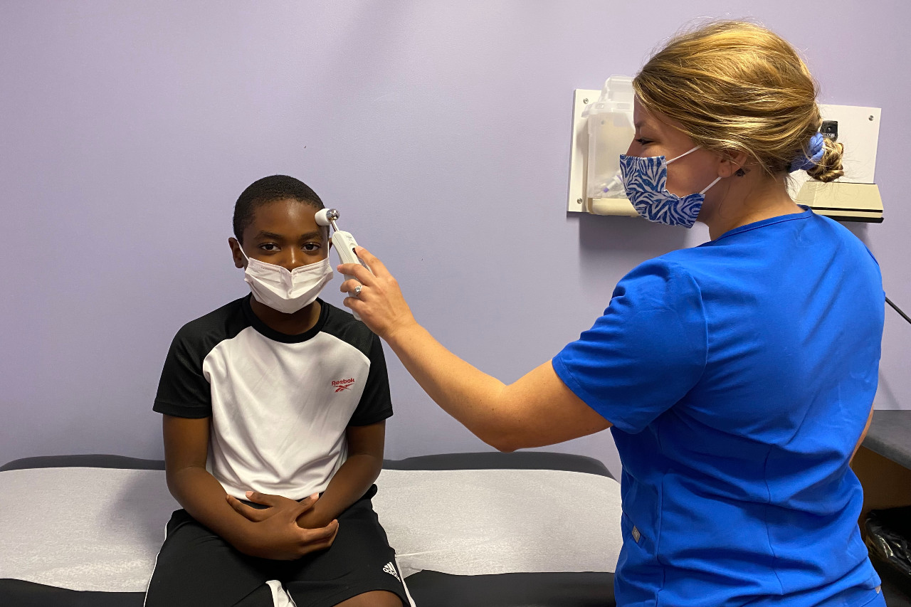 Clinician takes boy's temperature with forehead thermometer