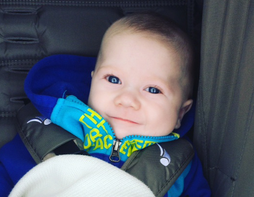 boy with cleft lip repair sits in car seat and smiles