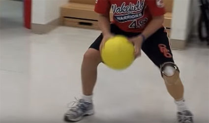 boy playing basketball with prosthesis