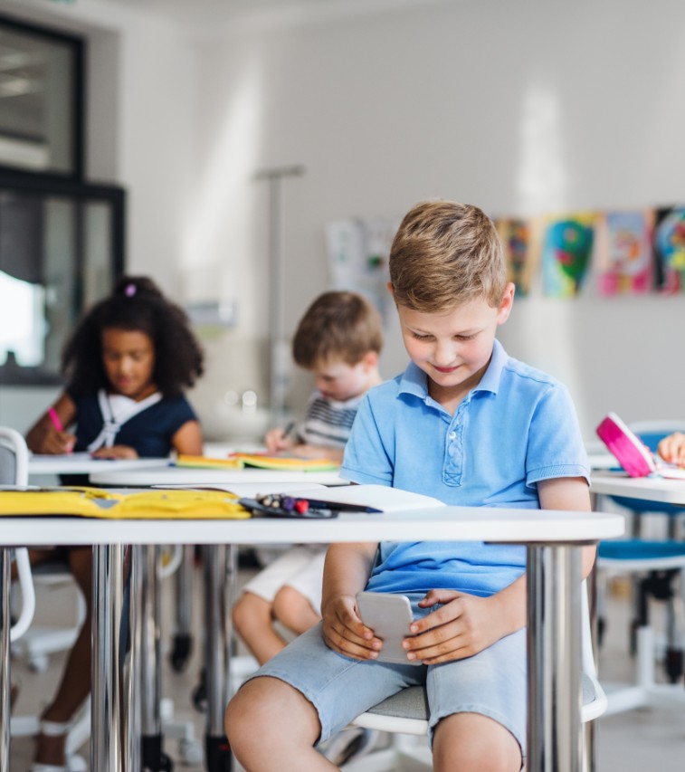 Boy looks at smartphone during class