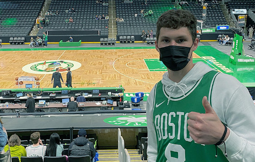 Connor, wearing a Celtics jersey, gives a thumbs-up while attending a Celtics game.