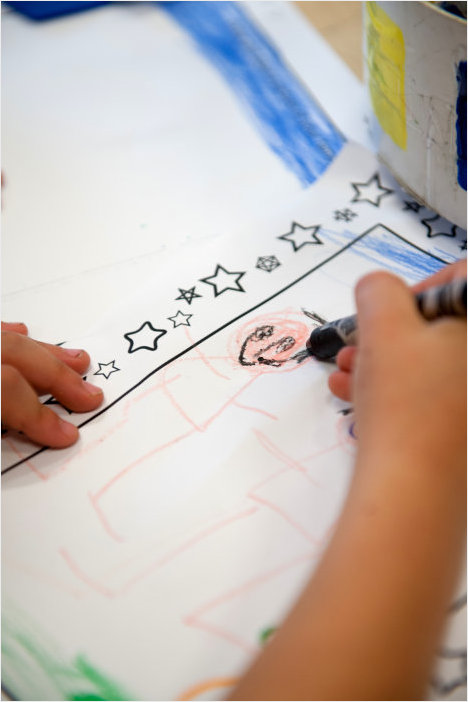 child drawing stick figures on a piece of paper