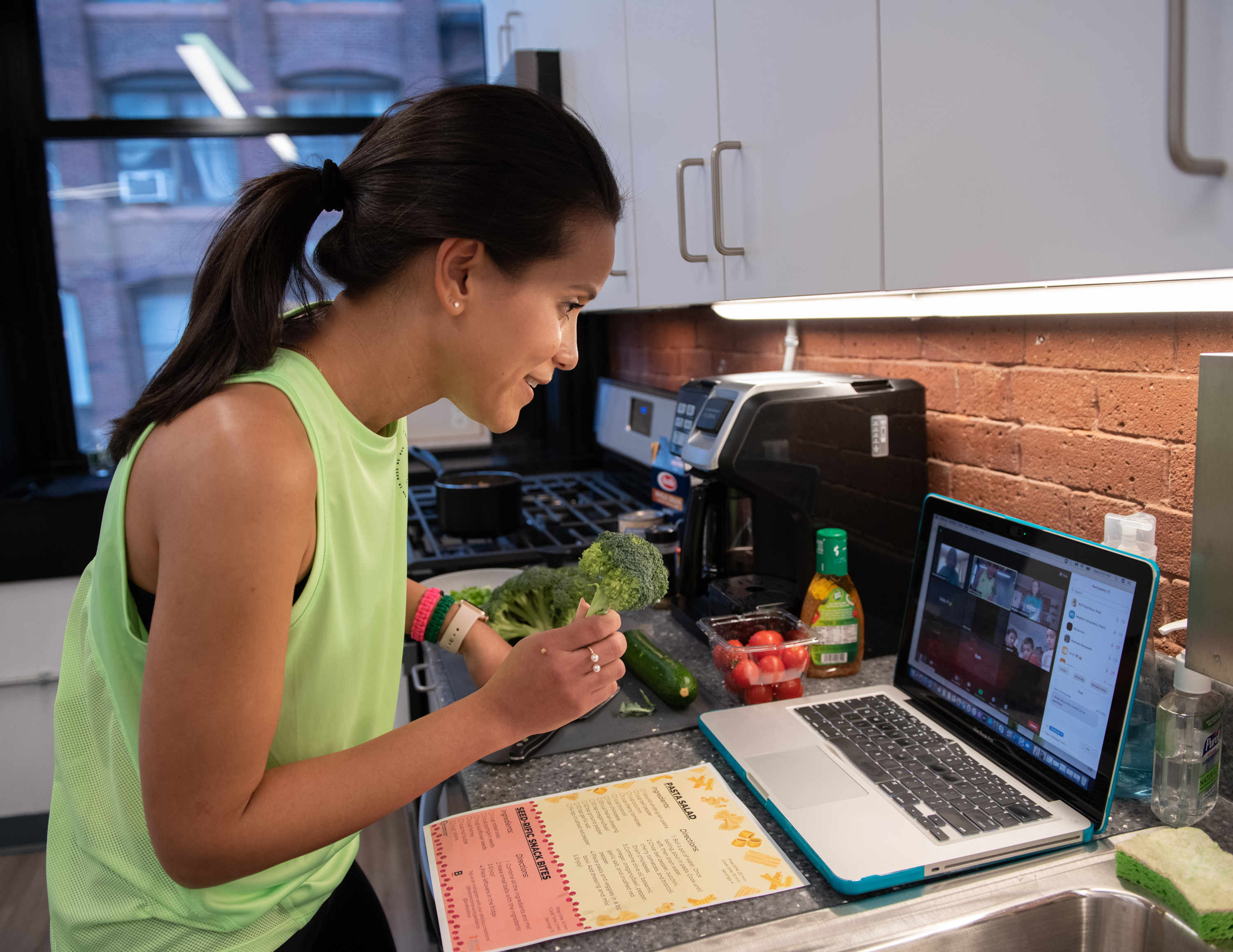 Woman looks into camera of laptop placed on a kitchen counter