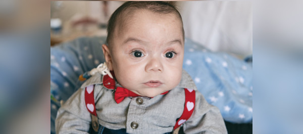 Baby with eyes wide open stares into the camera