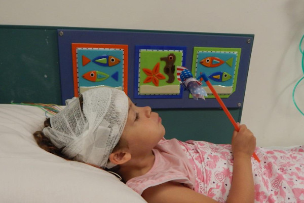 Girl lay on hospital bed and blows into pinwheel