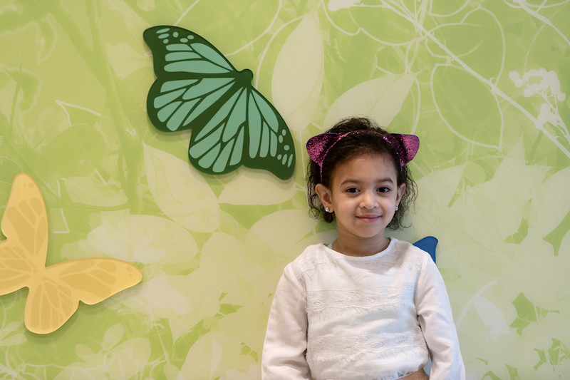 Girl stands in front of wall with butterfly icons