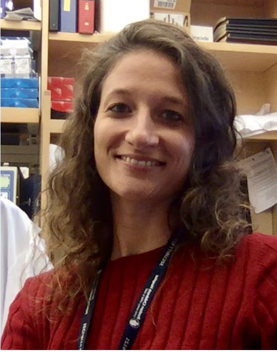 Headshot of Sara Bizzotto, a woman with curly brown hair who wears a red sweater smiles at the camera.