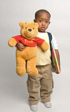 Boy hold backpack, book and stuffed Winnie the Pooh bear
