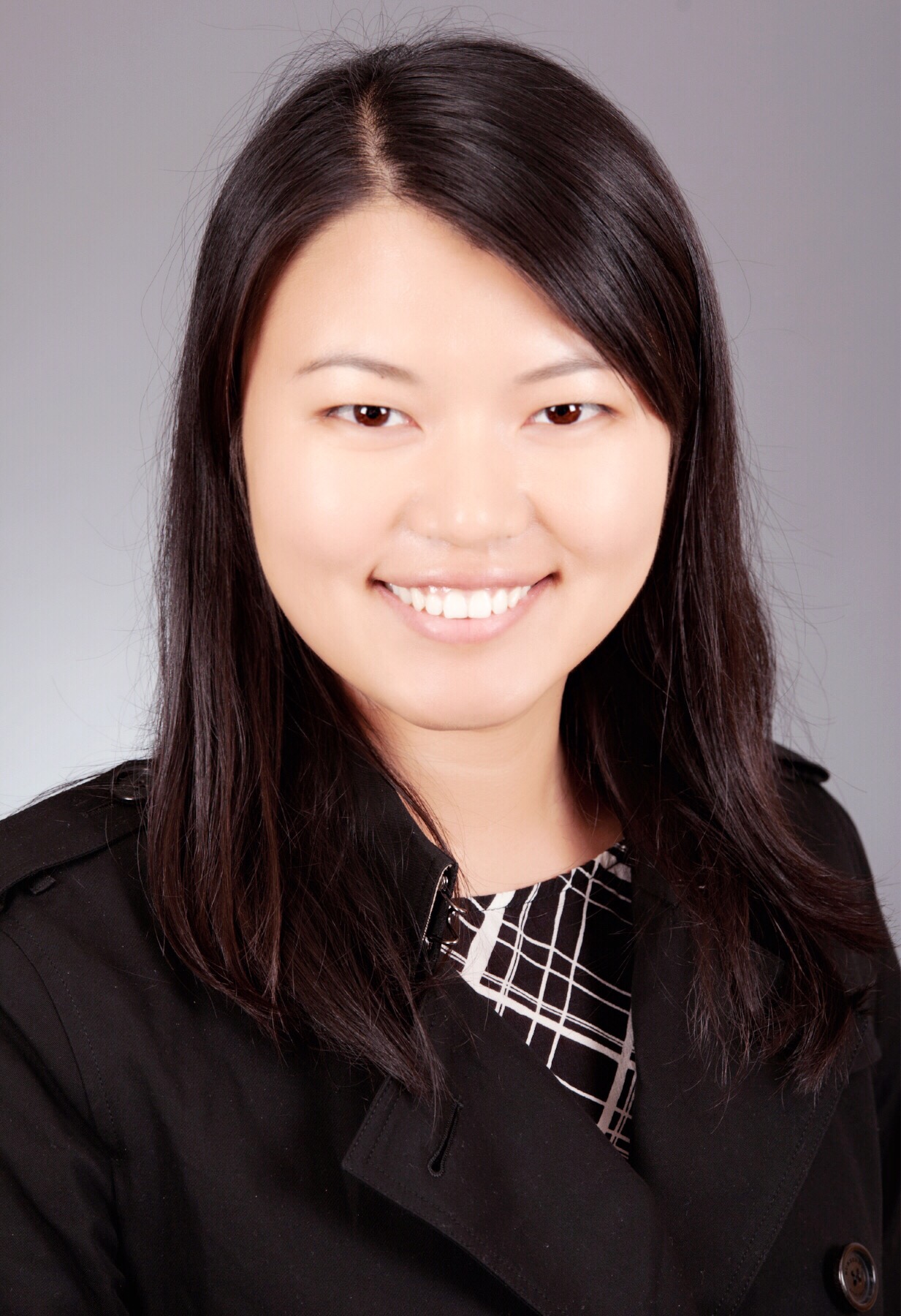 Headshot of Zhonghie Fu, a woman with sleek dark hair  wears a blazer over a plaid dress and smiles at the camera. 