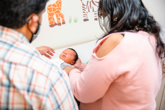 a mother and father looking down at a tiny baby