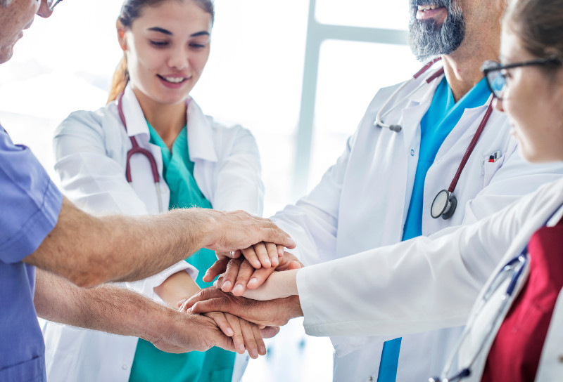 group of physicians with their hands in to cheer