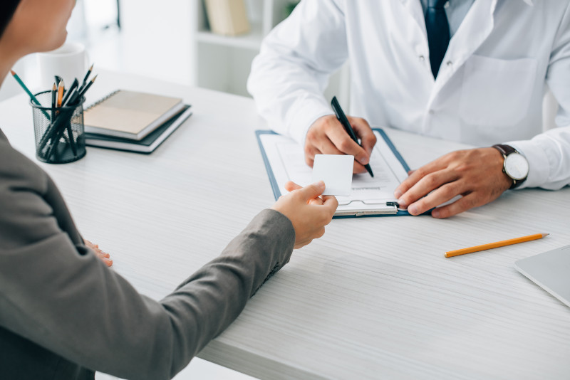 a woman handing over a card to a doctor