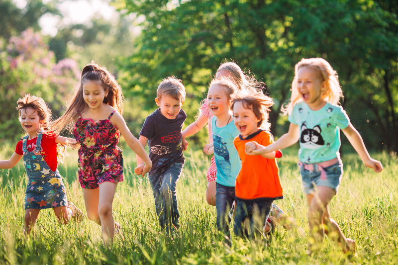 young kids frolicking through a grassy field in sunlight