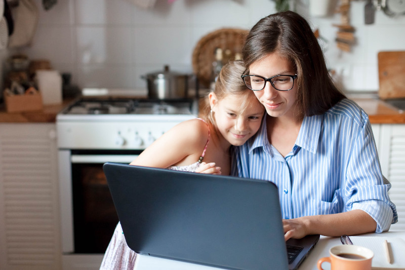 a mother and daughter looking at a computer