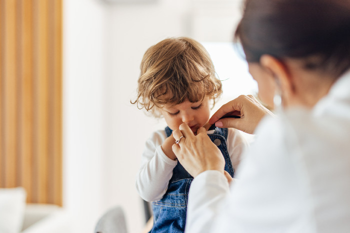 a pediatrician helping a young boy with his overalls