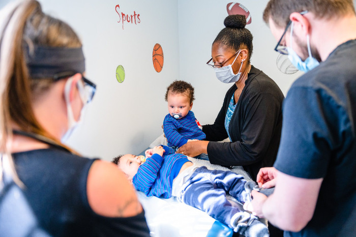 a group of medical people around two kids on an exam table