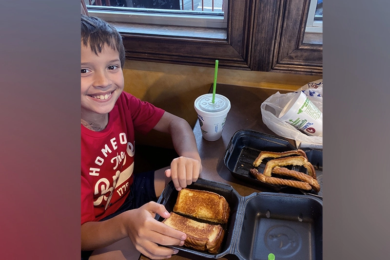 Benjamin, shown with a grilled cheese and French fries, can now eat solid foods after his surgery.