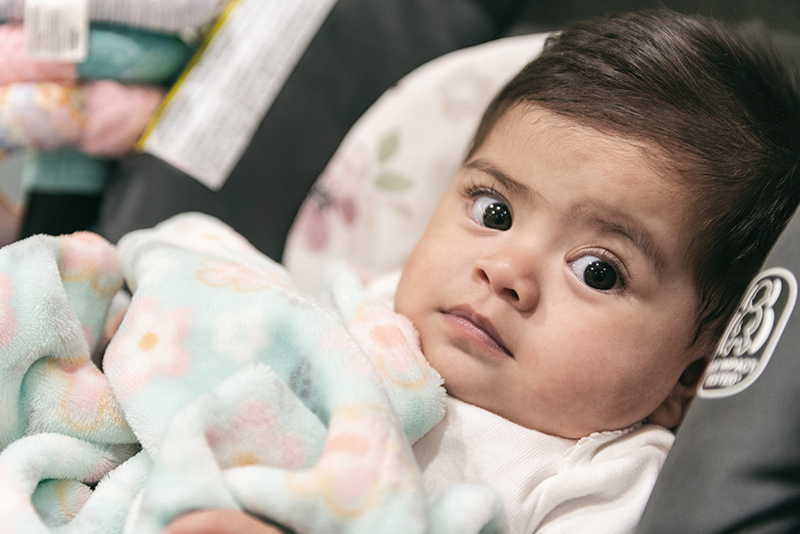 Dark-haired baby stares directly at the camera.