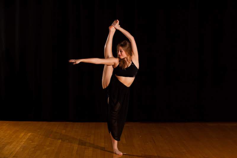 Female dancer fully holds up right leg while doing body stretches