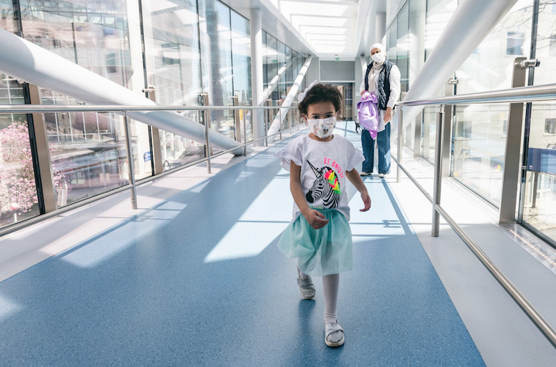 A young girl walks across sky bridge with her mom following her.