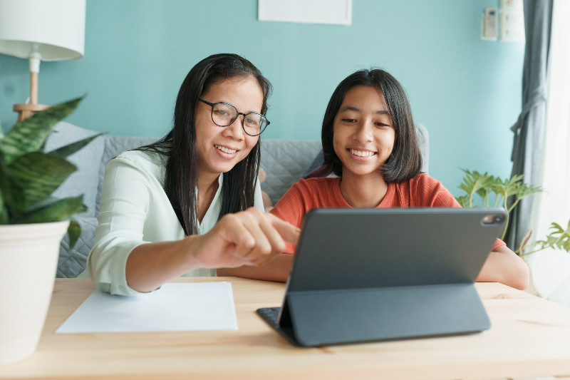 a mother and daughter looking at a tablet computer