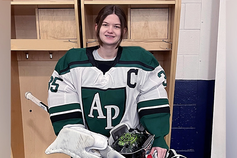 Hockey goalie sits in locker room wearing full uniform and equipment