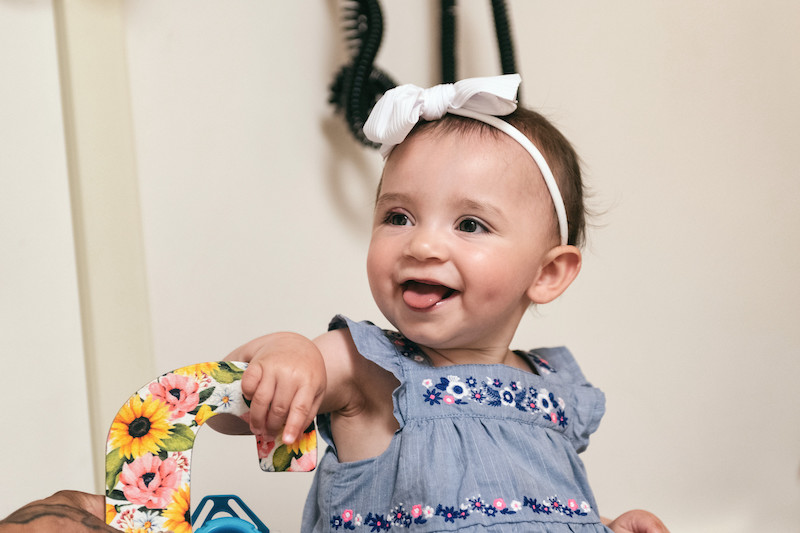 Young girl wearing dress and with bow in her hair looks away from camera