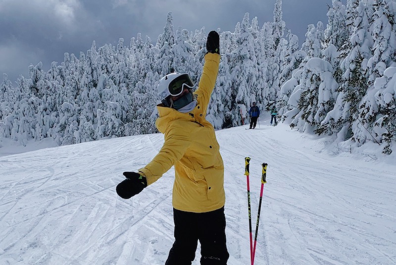 Teen wearing winter parka and ski goggles stands on skis