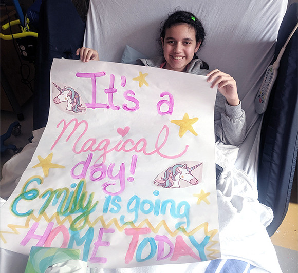 a girl in a hospital bed holding up a sign about going home
