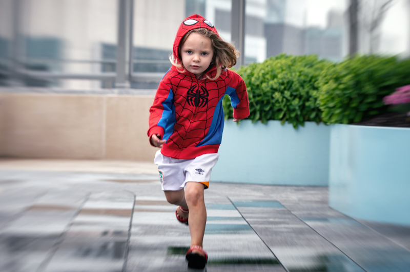 Young girl wearing Spiderman sweatshirt runs through garden