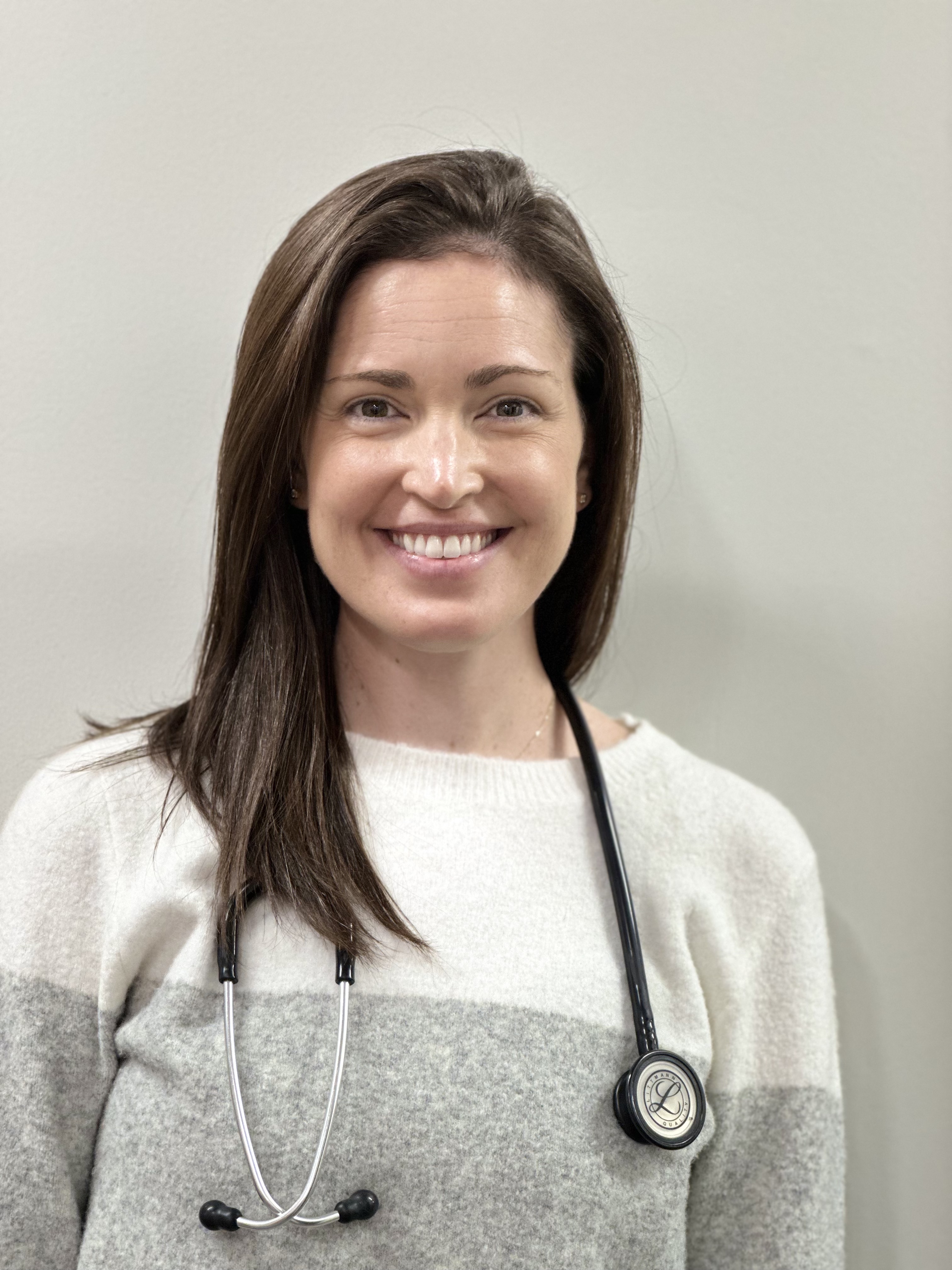 a beautiful woman smiling at the camera with a stethoscope around her neck