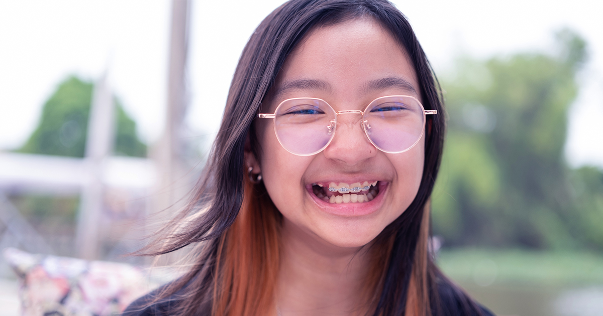 Young girl with glasses has open smile showing off braces
