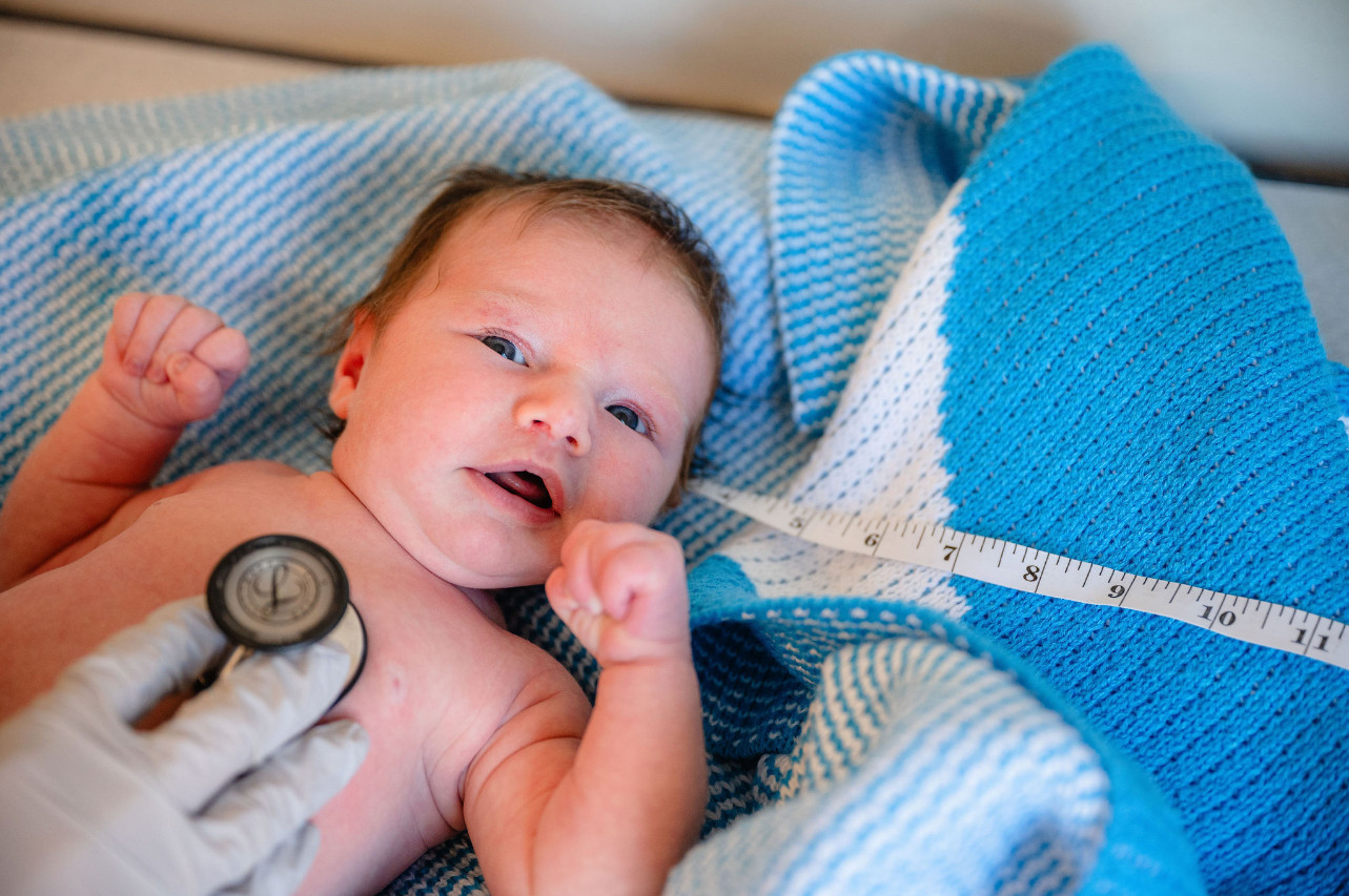 a newborn looking up with a stethoscope over his chest
