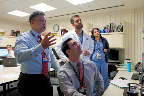 Four doctors in business clothes staring up at something out of frame