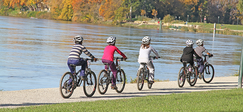 5 kids biking along path near the water