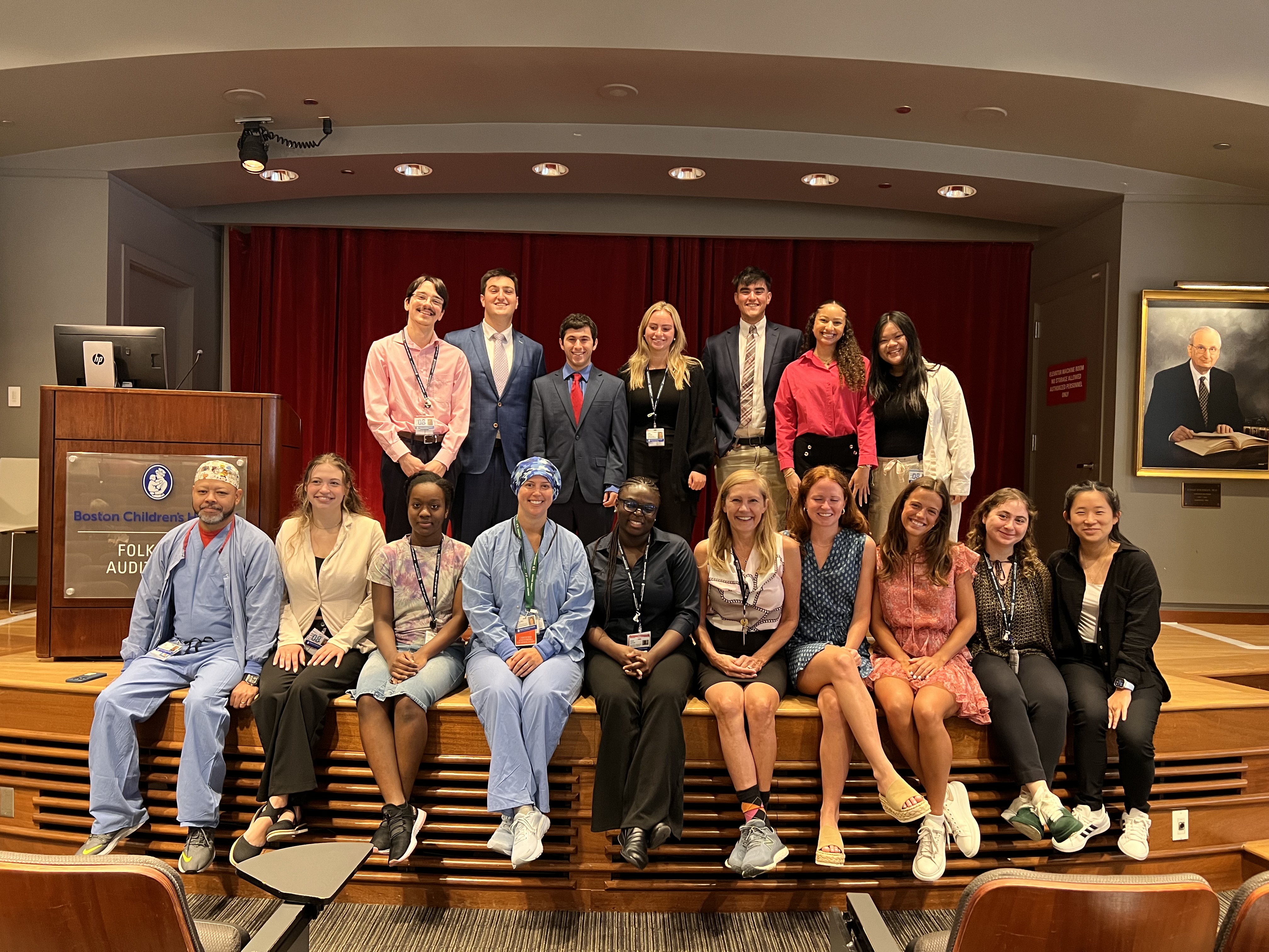 Interns stand and sit on stage when posing for group photo