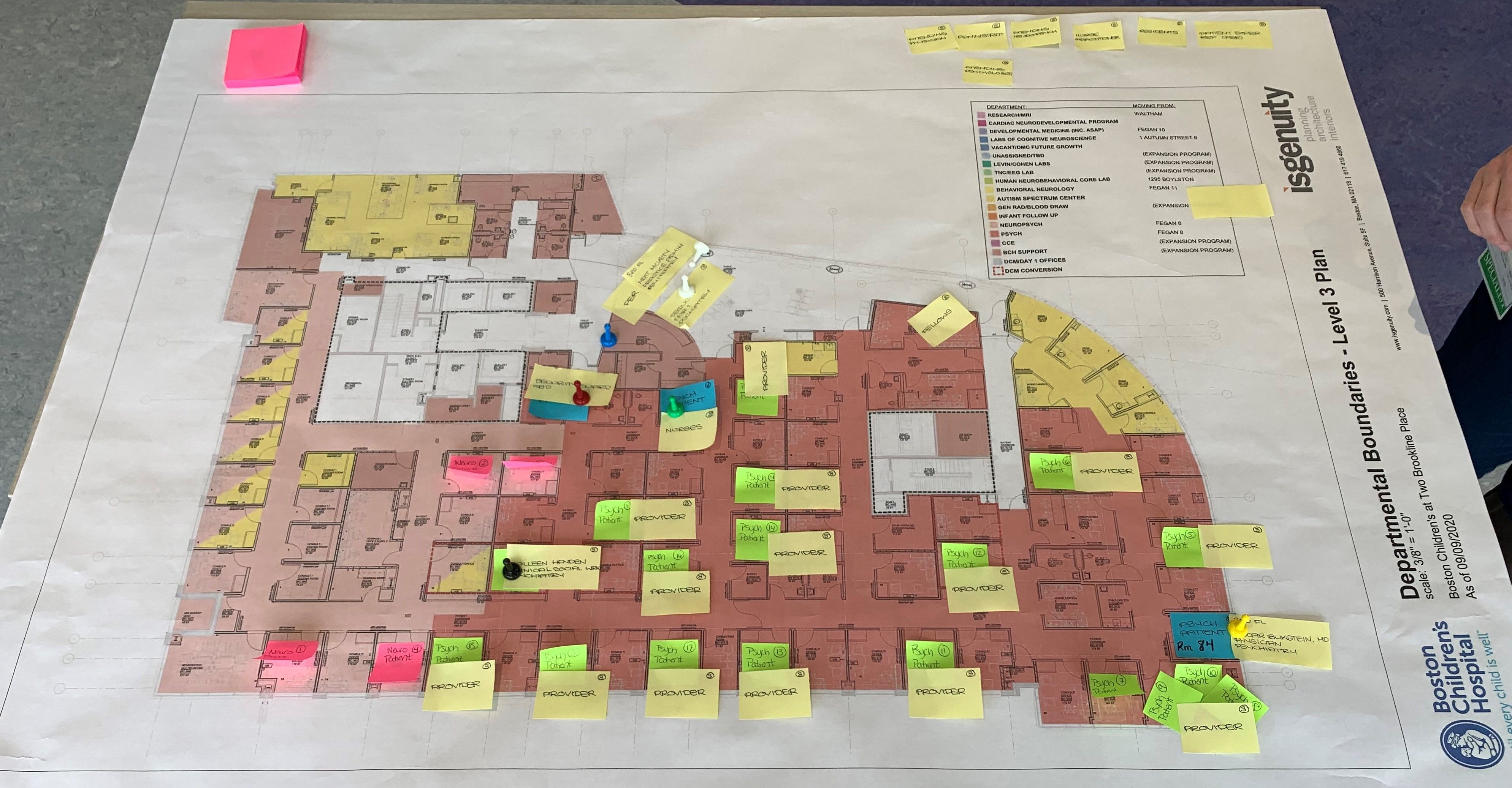 Pink, green, and yellow post-it notes layer on top of a red and pink map of the building. 