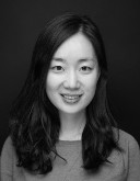 A black and white photo of April Choi, a woman with dark hair who smiles straight at the camera for her headshot.
