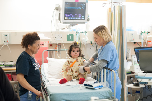 girl on hospital bed with nurses by her side