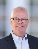 Headshot of Hans Oettgen, a white haired man who is wearing glasses and a dark blue blazer over a blue shirt.