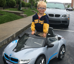 Mikey stands on top of electric mini BMW