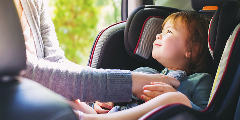 Mom putting baby into car seat