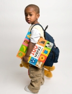 young child wearing a backpack and holding books