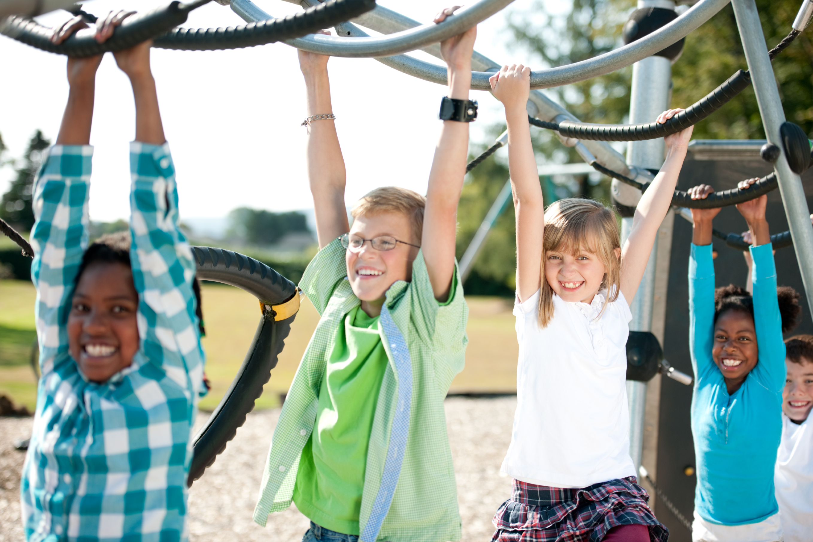 children in colorful shirts playing on the monkey bars and smiling